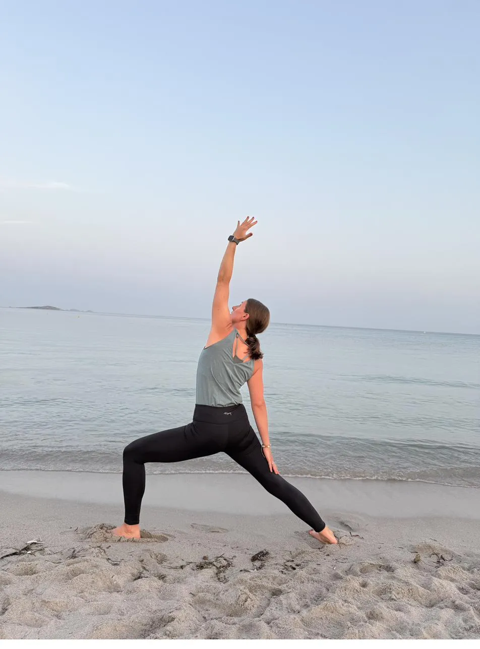 Yogalehrerin in umgekehrter Kriegerhaltung am Meer, Blick nach oben